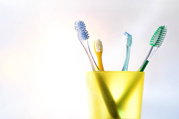 nettoyage dentaire quotidien de la famille avec une tasse en plastique jaune avec des brosses à dents - toothbrush plastic multi colored hygiene photos et images de collection