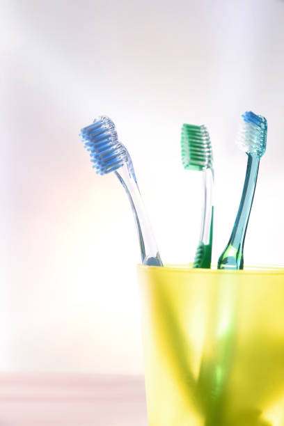 nettoyage dentaire familial quotidien avec verre jaune avec brosses à dents verticales - toothbrush plastic multi colored hygiene photos et images de collection