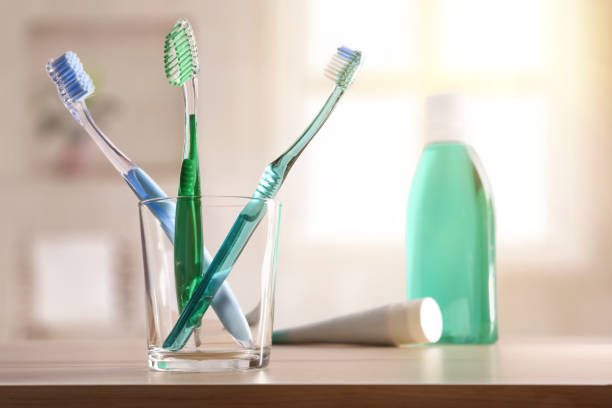 vidro com as escovas de dentes na tabela de madeira na composição geral do banheiro - toothbrush dental hygiene glass dental equipment - fotografias e filmes do acervo
