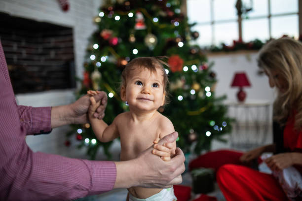 niño pequeño en pañales delante del árbol de navidad - two parent family naked men couple fotografías e imágenes de stock