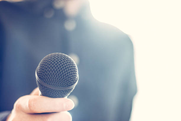 istock Journalist is holding a microphone in the foreground, blurry background 1134494021