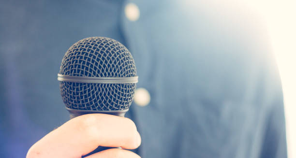 istock Journalist is holding a microphone in the foreground, blurry background 1134494845