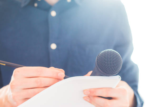 istock Male journalist at news conference, holding microphone and taking notes 1134494889