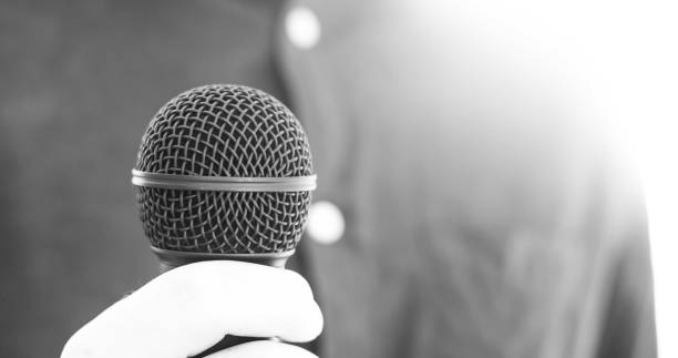 istock Journalist is holding a microphone in the foreground, blurry background 1134494942