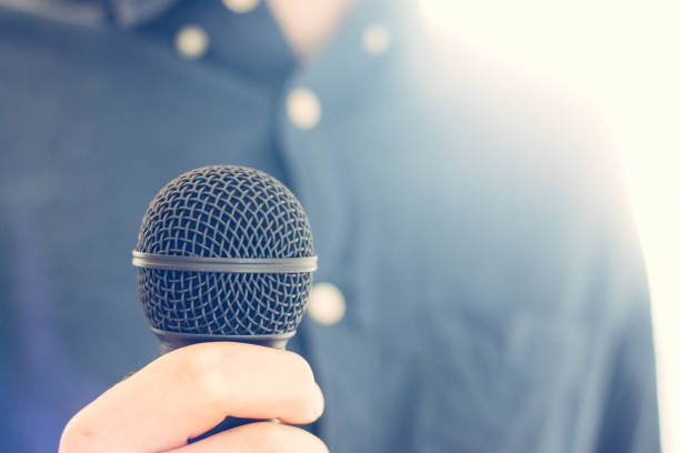 istock Journalist is holding a microphone in the foreground, blurry background 1134495083