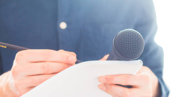 istock Male journalist at news conference, holding microphone and taking notes 1134495672