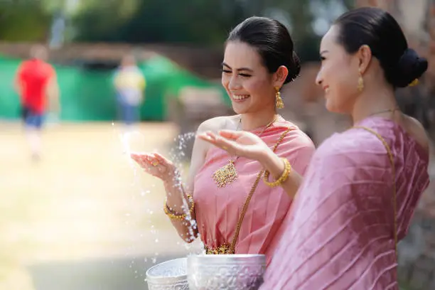 Songkran festival in Thailand. Happy Thai girls in Thailand cultural costume play water in the Thai new year festival called Songkran day.