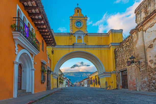 Antigua at Sunrise, Guatemala The Agua volcano illuminated by the first sunlight at sunrise seen from the main street of Antigua city, famous for its yellow arch, Guatemala, Central America. agua volcano photos stock pictures, royalty-free photos & images