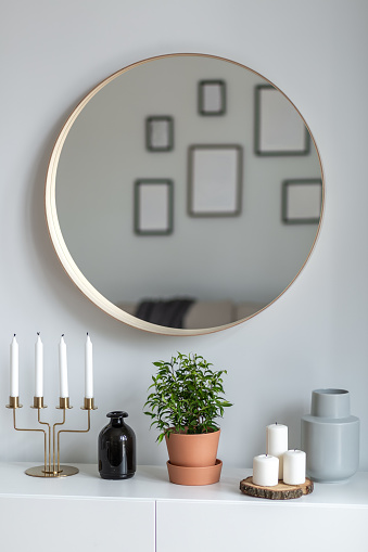 Home interior with simple, round mirror and white sideboard