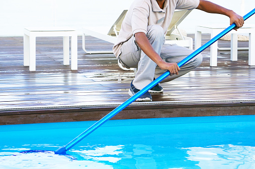 Pool cleaner during his work. Hand african hotel staff worker cleaning the pool.
