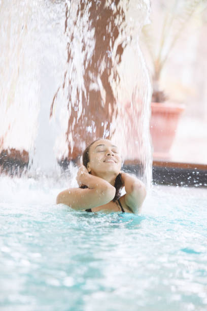 istock Cheerful woman under spa waterfall jet 1134506383