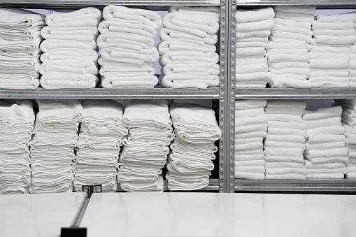 White clean towels laid out on the shelves. Hotel linen cleaning services. Hotel laundry