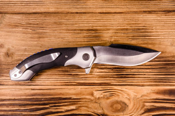 istock Opened folding knife on a wooden table. Top view 1134510232