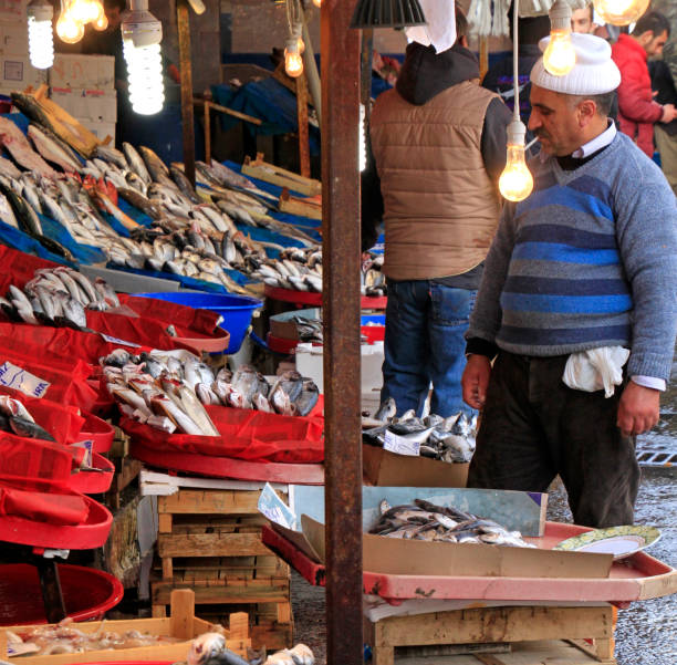 Istanbul, Turkey - February 15, 2019: Fisherman in Istanbul selling the catch of the day on a fish market while smoking a cigarette
