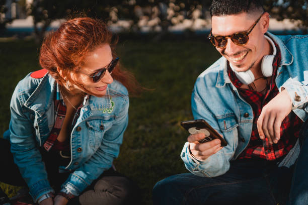 istock Happy young couple in love using smartphone while sitting in a green park 1134512343