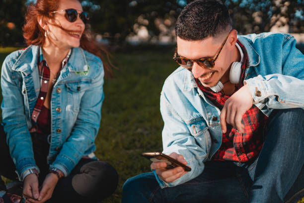 istock Happy young couple in love using smartphone while sitting in a green park 1134512411