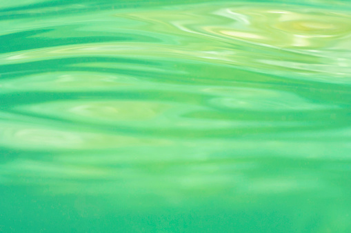 Underwater photograph of shallow sea surface. Yellow and green are the reflections of sand and sea weed respectively. Image made in Greece.