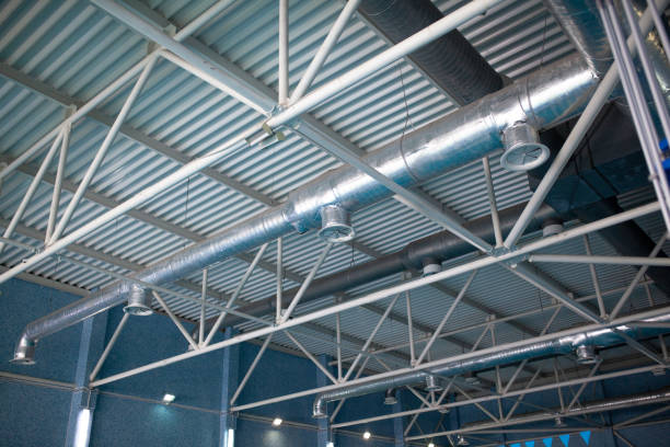 HVAC Duct Cleaning, Ventilation pipes in silver insulation material hanging from the ceiling inside new building Ventilation system on the ceiling of large buildings. Ventilation pipes in silver insulation material hanging from the ceiling inside new building new big tube stock pictures, royalty-free photos & images