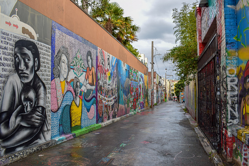 Bogota, Colombia - May 28, 2018: A colorful street in the historic La Candelaria District in the capital city of Bogota in the South American country of Colombia. Many of the walls in the area are painted in the vibrant colours of Colombia, sometimes depicting Pre-Colombian legends or modern Street Art and Graffiti. The altitude at street level is 8,660 feet above mean sea level. Photo shot in the late afternoon sunlight; horizontal format.