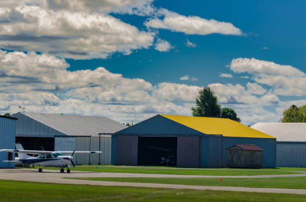 Small single prop engine aircrafts planes parked inside workshop hangar with closed door. Private ultralight at aerodrome