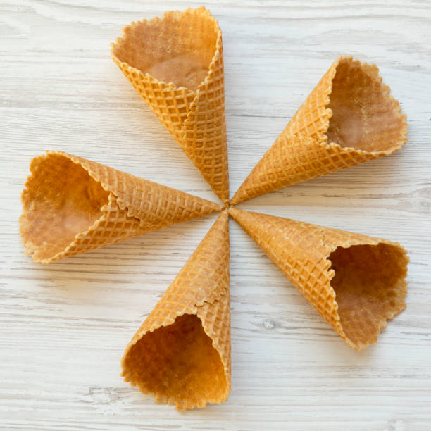 istock Five ice cream waffle cones on a white wooden surface, top view. From above, overhead. 1134519261