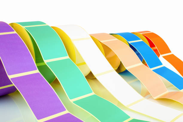 istock White and colored label rolls isolated on white background with shadow reflection. Color reels of labels for printers. Labels for direct thermal or thermal transfer printing. Close shot of stickers. 1134520389