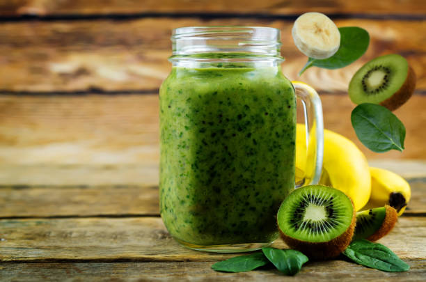 istock Spinach banana kiwi smoothie on a dark wood background 1134522883