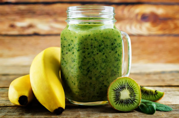istock Spinach banana kiwi smoothie on a dark wood background 1134522885