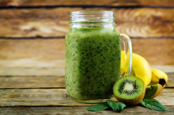 istock Spinach banana kiwi smoothie on a dark wood background 1134522899