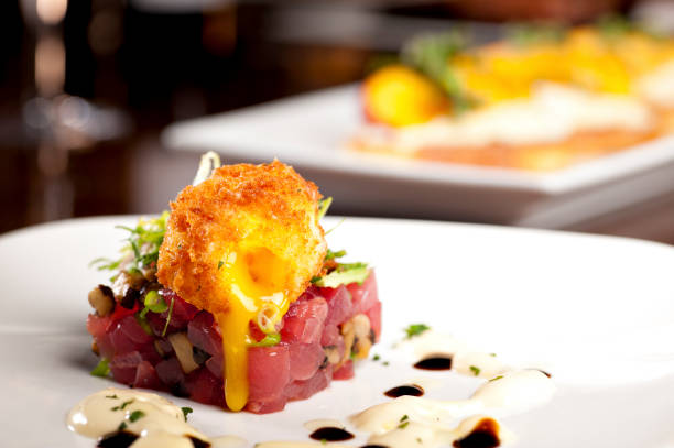 Delicious Ahi Tuna Tartare with Deep Fried Soft Boiled Egg served with sauce on a white plate