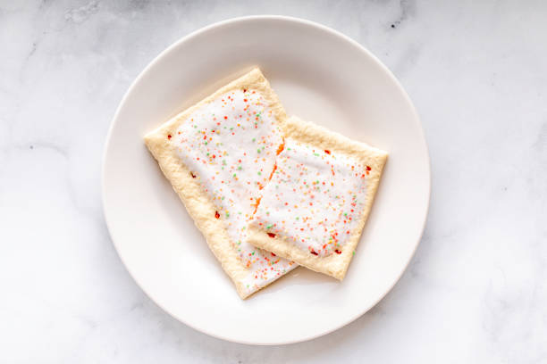 Toaster Pastries A toaster pastry with frosting, sprinkles, and red strawberry or cherry filling biscuit quick bread stock pictures, royalty-free photos & images