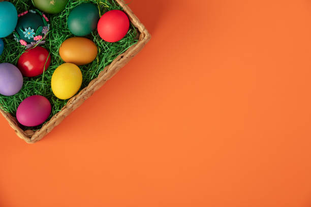 Top view of colorful easter eggs in basket on grass and straw nest