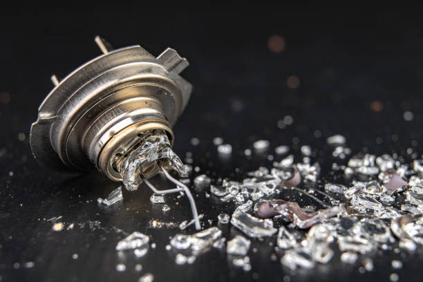 istock Broken bulb for the car headlight. Spilled glass and broken filament on the workshop table. Dark background. 1134531677