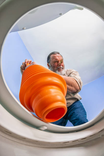 istock Looking up at a man using orange plunger to clear a clogged toilet 1134533428