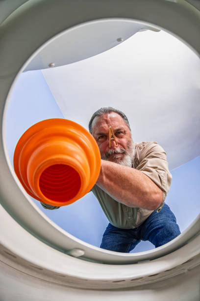 istock Looking up at a man using orange plunger to clear a clogged toilet 1134533453
