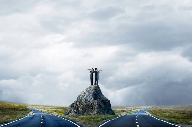 Business People Standing On Large Rock Looking At Fork In The Road