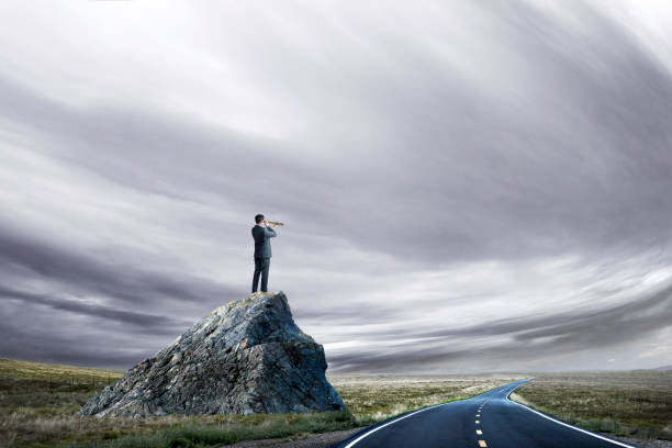 istock Businessman Looks Through Spyglass From A Perch On Large Rock 1134556680