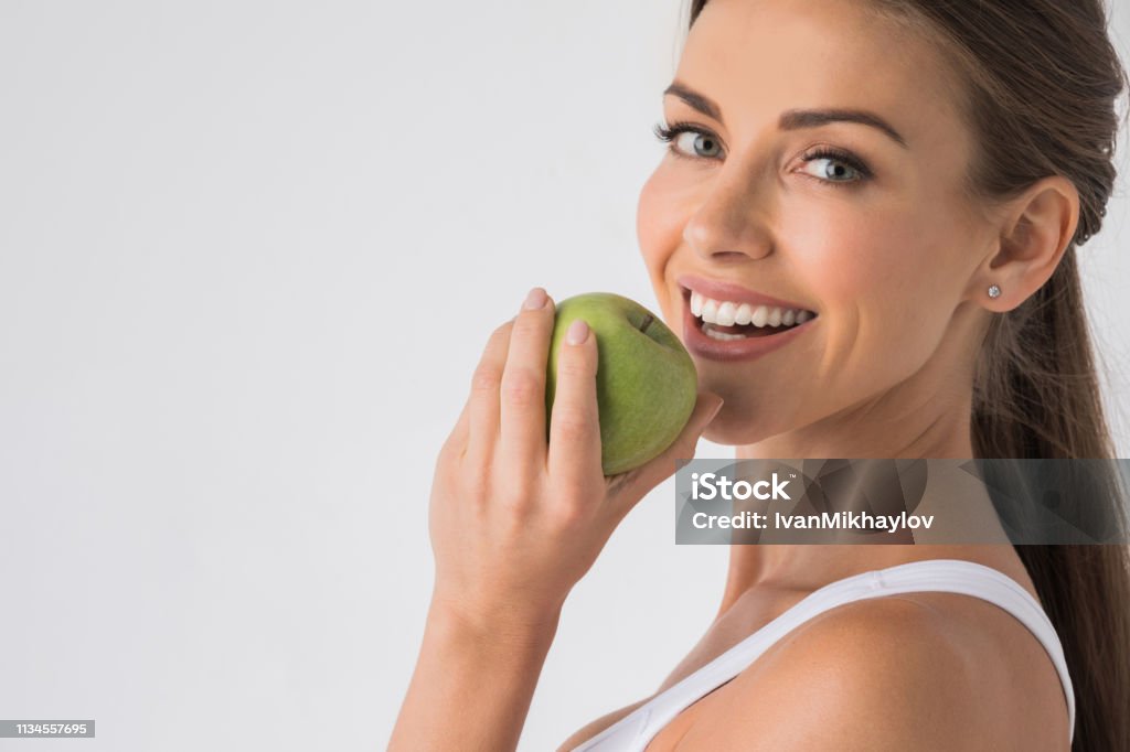 Woman biting green apple Young woman with healthy teeth smiling and biting green apple Teeth Stock Photo