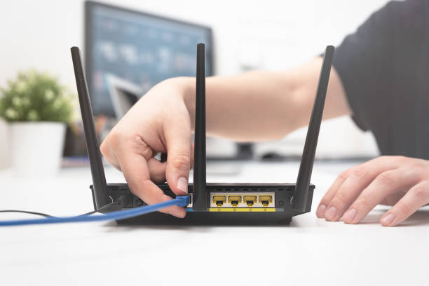 Man connects the internet cable to the router Man connects the internet cable to the router's socket. Fast and wireless internet concept router stock pictures, royalty-free photos & images