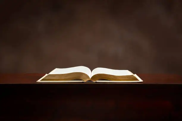 Horizontal shot of an old Bible lying open on a brown background.