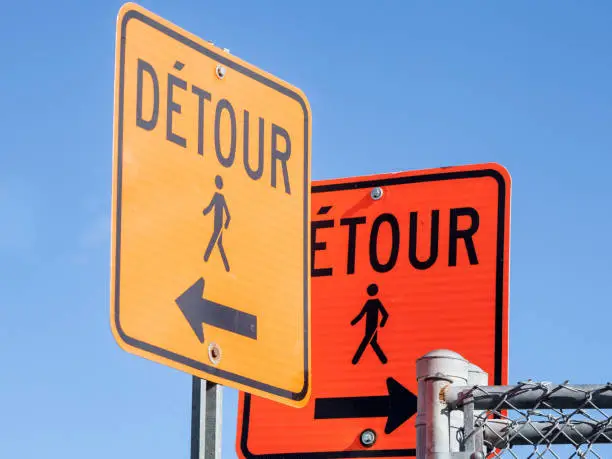 Photo of Two Detour road signs, orange color, complying with North American rules indicating a deviation for pedestrians in a street of Montreal, Quebec, Canada