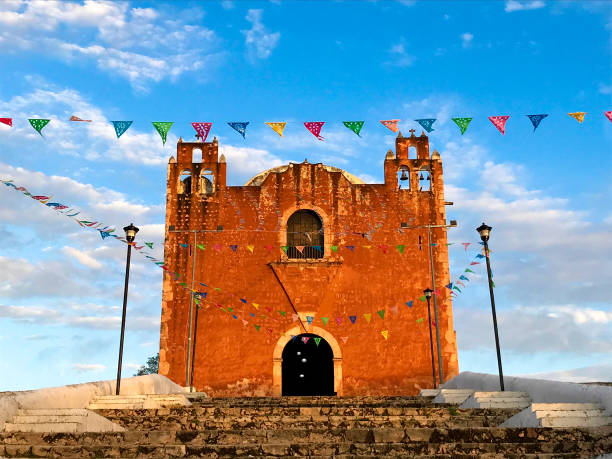 Santa Elena, Yucatan, Mexico: Orange Church at Sunset Santa Elena, Yucatan, Mexico: A vibrant sunlit orange church in Spanish Colonial style (shot at sunset) in Santa Elena, a Mayan village 10 kilometers from the Mayan Uxmal ruins in the Yucatan Peninsula, Mexico. The church is Templo de San Mateo. Copy space in the sky. uxmal stock pictures, royalty-free photos & images