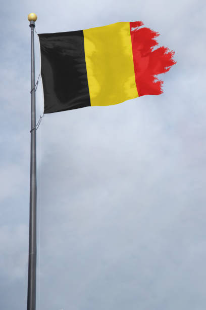 Worn and tattered Belgium flag blowing in the wind on a cloudy day