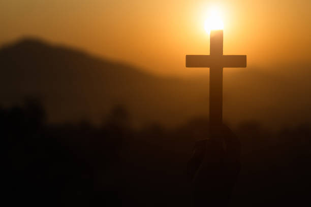 mano de la mujer que sostiene la elevación santa de la cruz cristiana con fondo ligero del atardecer. - praying human hand worshipper wood fotografías e imágenes de stock