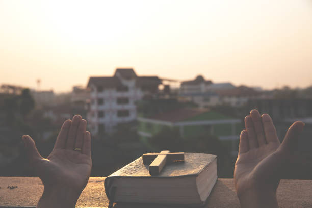 die frauen beten zu gott mit der bibel und dem kreuz mit dem morgendlichen sonnenaufgang. frau betet für gottes segen für den wunsch, ein besseres leben zu haben. christliches leben krise gebet zu gott. - praying god love wisdom stock-fotos und bilder