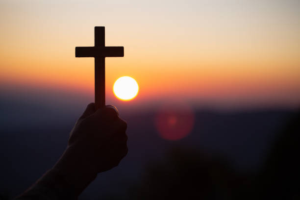 silhueta fora das mãos que prendem a cruz de madeira no fundo do nascer do sol, crucifix, símbolo da fé. - coral break - fotografias e filmes do acervo