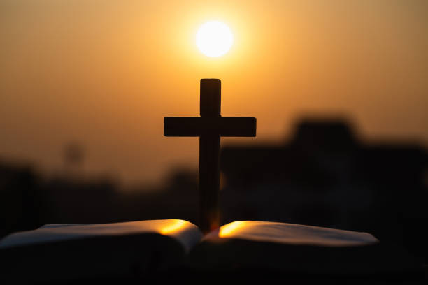 silhueta da cruz cristã de madeira na bíblia com um nascer do sol brilhante como o fundo, deus. - religious text cross protestantism reading - fotografias e filmes do acervo