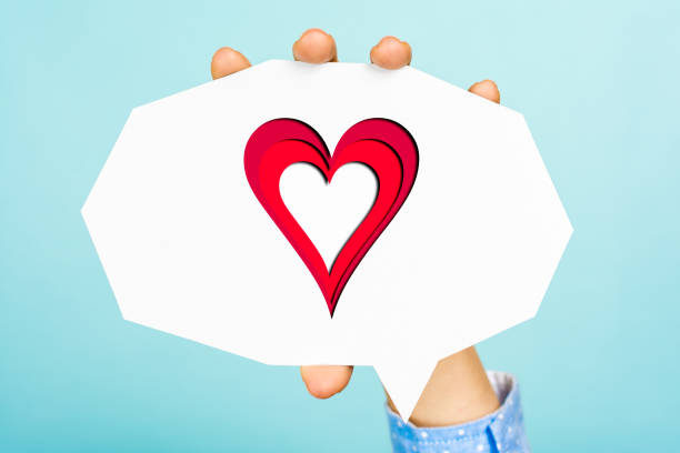 Hand showing a heart shape on empty white speech bubble with straight cutting shape, all this on blue background.