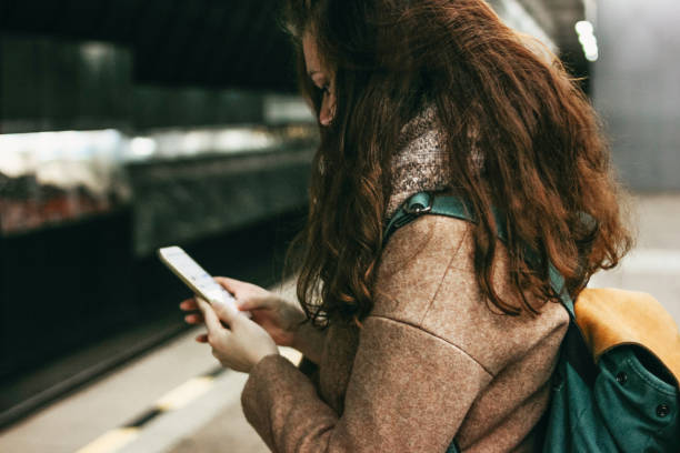 istock Young woman curly red head girl traveller with backpack using mobile in subway 1134598128