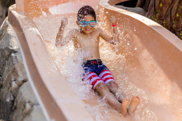 szczęśliwe dziecko za pomocą zjeżdżalni wodnej do basenu - cannonball zdjęcia i obrazy z banku zdjęć